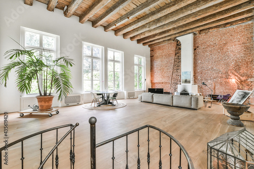 Big room with high wood beamed ceilings furnished with gray couch and art design elements in minimalist style photo