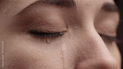 Girl eyes having long nice Eyelashes. Close up of Caucasian woman crying with tear. Close Up Macro Zoom Shot of a Crying Eyes. Tears are Flowing Down. Young Beatiful brunette Female crying.