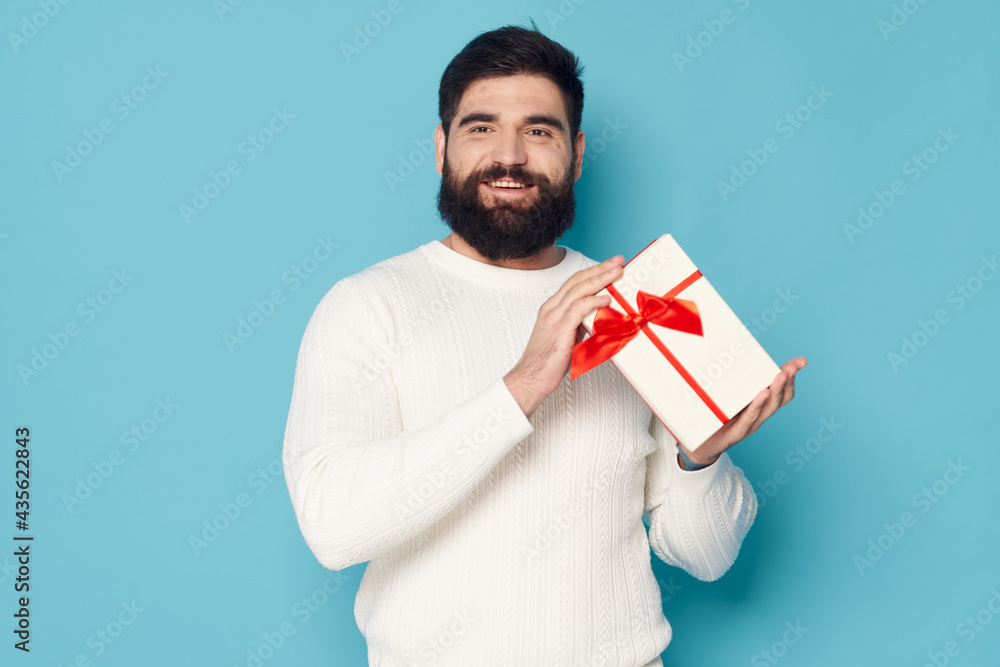 bearded man with a gift in his hands white sweater gift as a holiday bearded man with a gift in his hands white sweater gift as a holiday