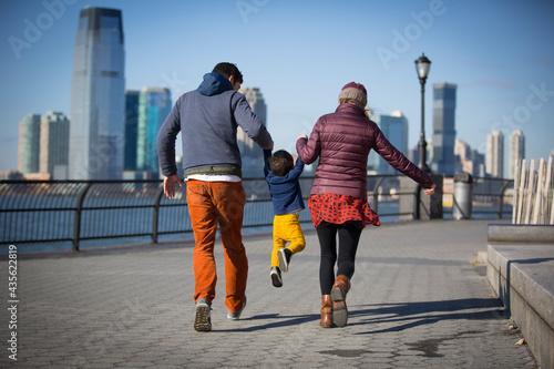 young couple with their kid walking by the river in New York