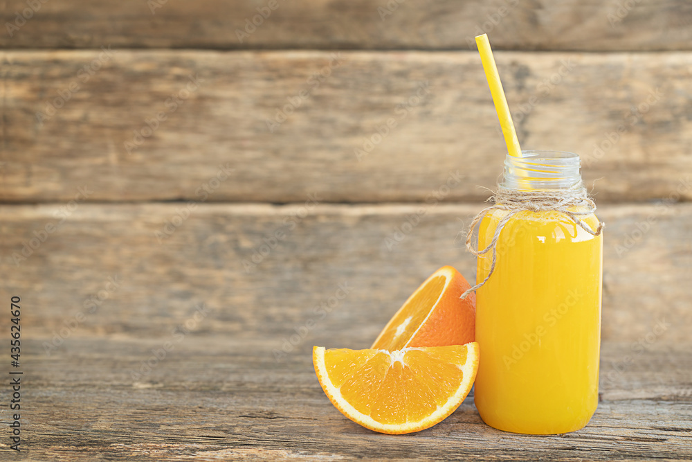 Fototapeta premium The bottle of orange juice and sliced orange on the wooden background