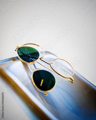 getönte Sonnenbrille zum aufstecken an goldenes Brillengestell auf blauen Leder