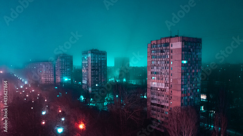 Neon lighted urban aerial panorama in a bad ghetto district. Deep blue colored light just from the dark on the horizon