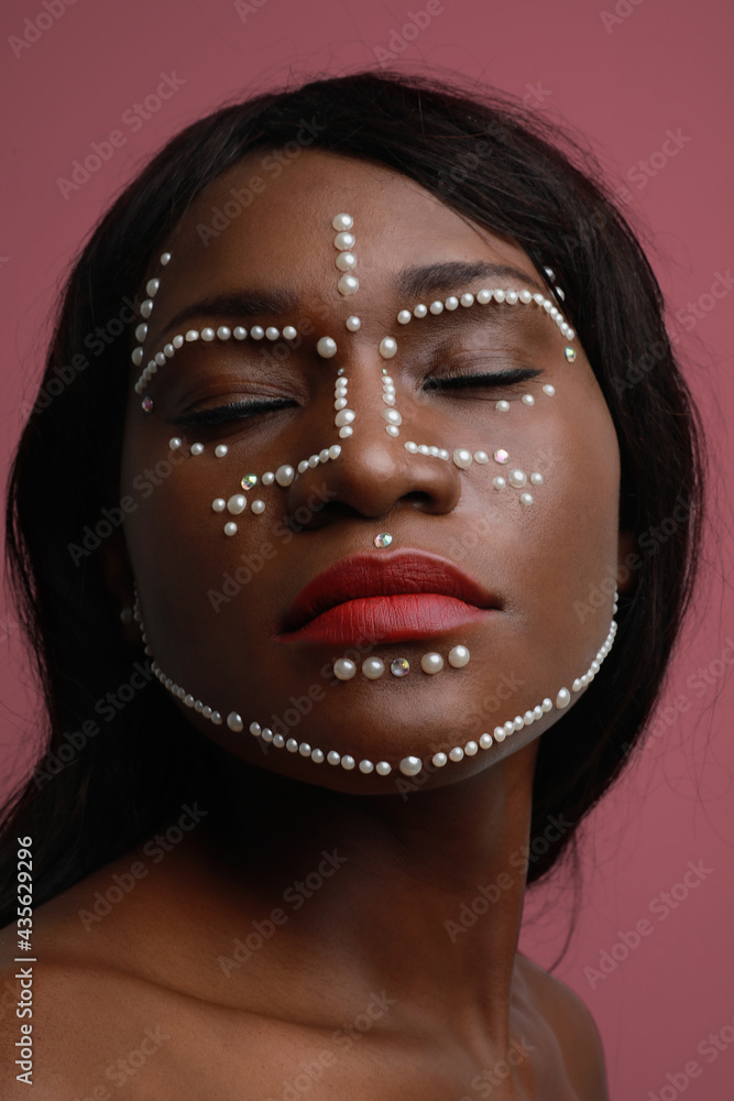 Vertical close-up portrait of attractive black woman with pearls on her face. 