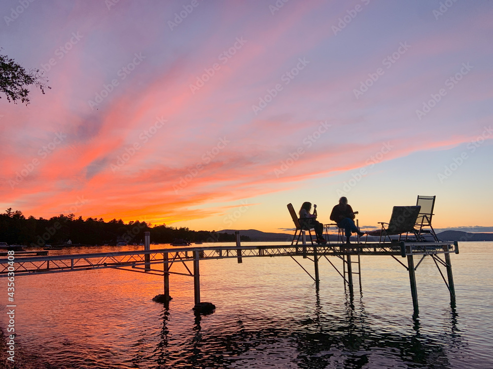 Mother and daughter play ukulele's together on a dock over Sebago Lake, Maine Mother and daughter play ukulele's together on a dock over Sebago Lake, Maine
