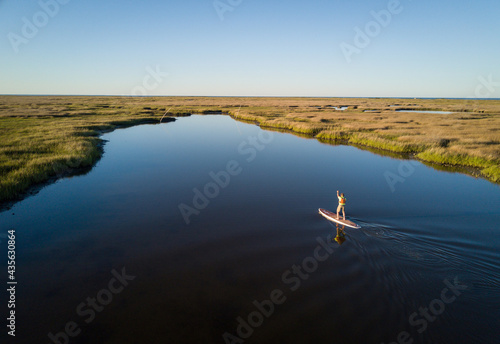 Stand up paddle boarder paddles through a Chesapeake Bay salt marsh near Hampton, Virginia