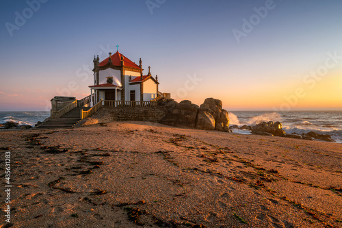 Beautiful chapel of Capela do Senhor da Pedra on the beach at sunset in Miramar, Vila Nova de Gaia, Portugal photo