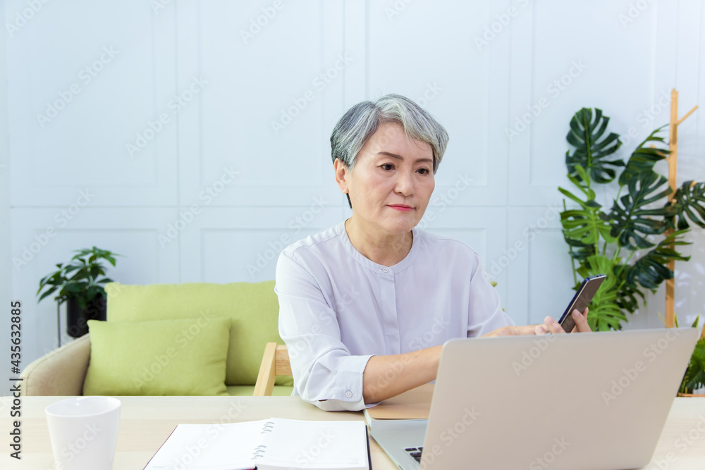 Senior Asia woman is working from home, using laptop and smart phone. Senior Asia woman is working from home, using laptop and smart phone.