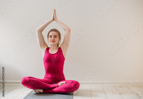 Fototapeta Naklejka Na Ścianę i Meble -  Young healthy beautiful woman practicing yoga at home sitting in lotus pose on yoga mat meditating relaxed. Indoor and outdoor workout. Sport and healthy active lifestyle concept.