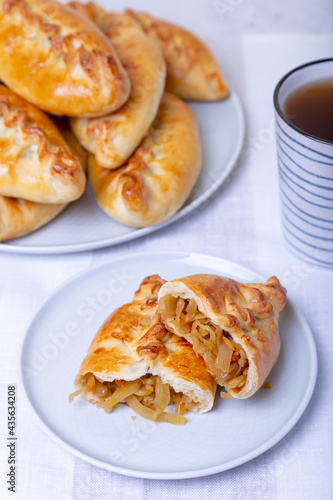 Pies (pirozhki) with cabbage. Homemade baking. Traditional Russian and Ukrainian cuisine. In the background is a dish with pies. Close-up.