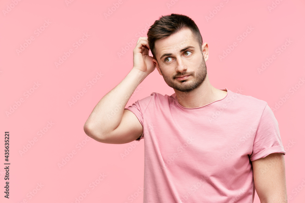 Young pensive man have doubts while scratching head looking to copy space on pink background Young pensive man have doubts while scratching head looking to copy space on pink background