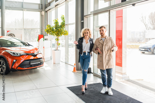 Young beautiful couple enters to car dealership