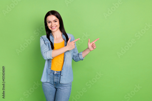 Photo of positive nice brown long hairdo lady point empty space wear jeans shirt isolated on pastel green color background