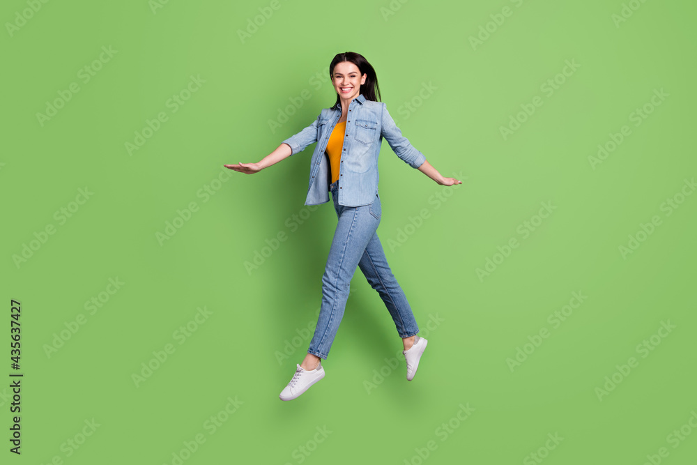 Full length profile photo of cheerful nice brown hairdo lady jump wear jeans shirt isolated on pastel green color background Full length profile photo of cheerful nice brown hairdo lady jump wear jeans shirt isolated on pastel green color background