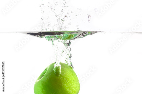 drop one green apple into the water with splashes on a white background