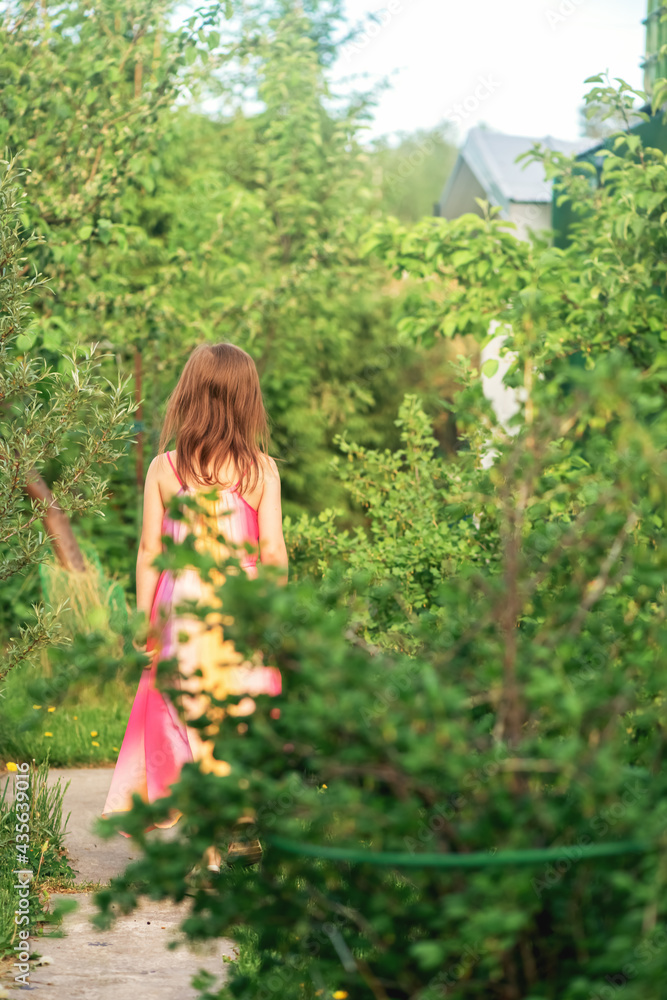 Girl in dress walks through the garden Girl in dress walks through the garden