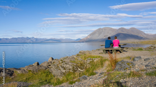 Man and Woman couple at a picnic table traveling and camping in waterfront Iceland