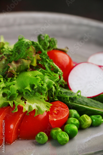 salad with fresh vegetables on plate closeup. salad with tomatoes peas cucumber radishes
