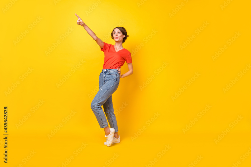 Full size photo of optimistic nice brunette lady point empty space wear orange t-shirt isolated on yellow background Full size photo of optimistic nice brunette lady point empty space wear orange t-shirt isolated on yellow background