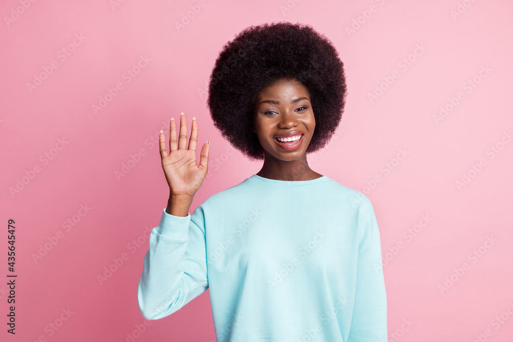 Photo of happy nice dark skin woman wave hand hello good mood smile isolated on pink color background Photo of happy nice dark skin woman wave hand hello good mood smile isolated on pink color background