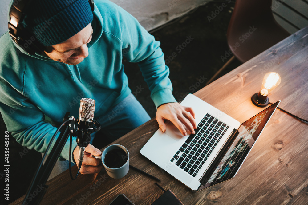 Handsome content creator streaming his live podcast using professional microphone at his broadcast studio Handsome content creator streaming his live podcast using professional microphone at his broadcast studio