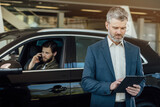 Buying a new car. Car dealer selling car using digital tablet.