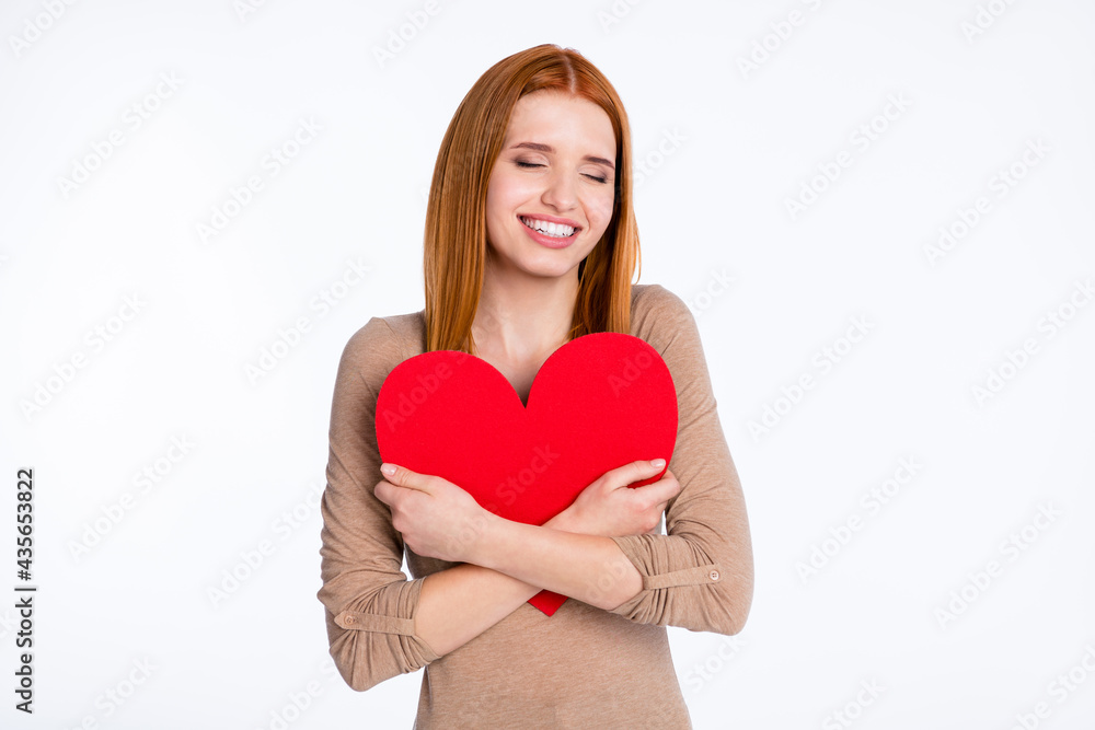 Photo of charming cute redhair woman beige shirt hugging large red heart smiling closed eyes isolated white color background Photo of charming cute redhair woman beige shirt hugging large red heart smiling closed eyes isolated white color background