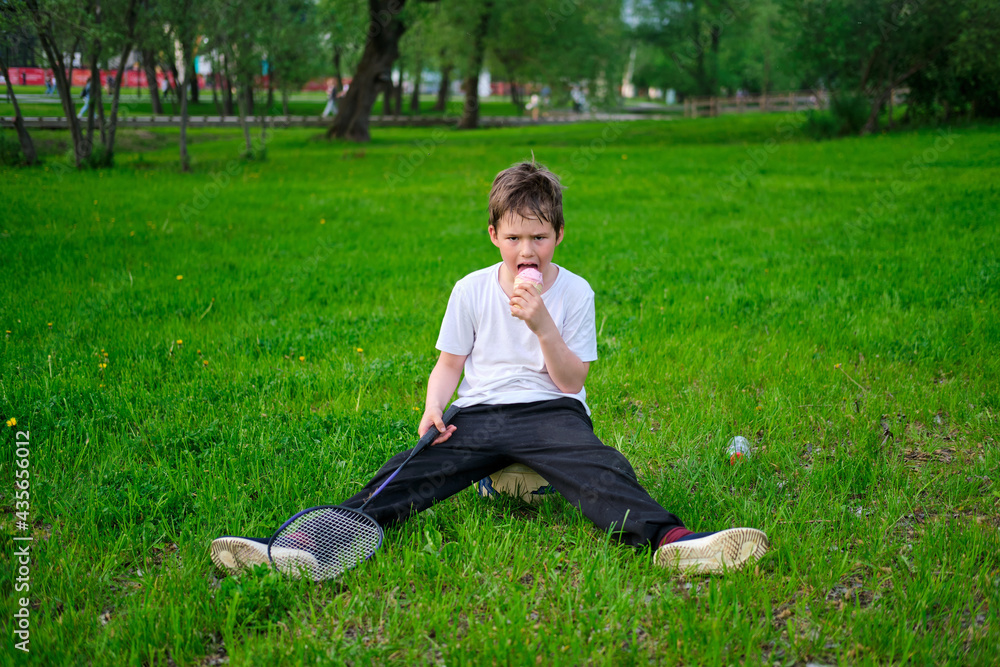 Boy on vacation after playing sports with ice cream on the park lawn