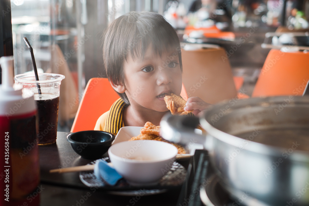 Little Asian toddler boy tries to eat crispy fried food at restaurant Little Asian toddler boy tries to eat crispy fried food at restaurant
