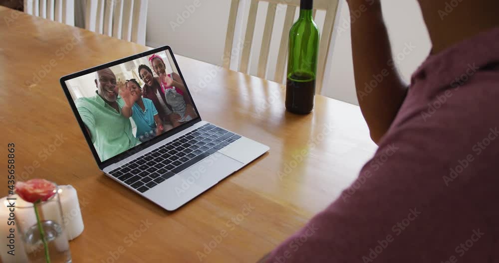Mixed race man sitting at table using laptop making video call with family Mixed race man sitting at table using laptop making video call with family