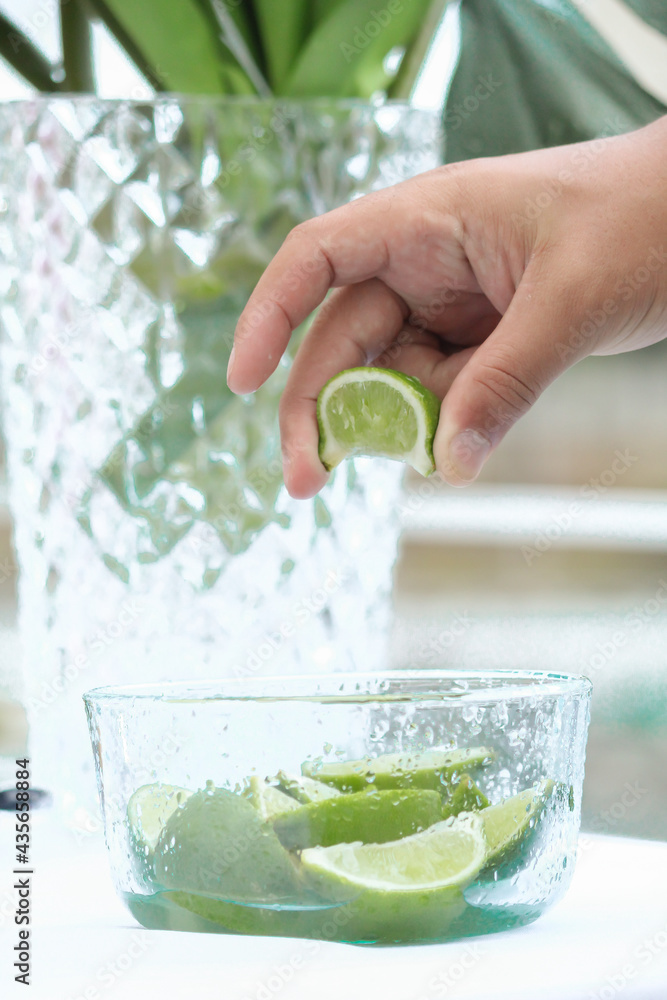 una persona exprime un limón de una pequeña jarra con limones cortados, fruta ácida Stock Photo una persona exprime un limón de una pequeña jarra con limones cortados, fruta ácida Stock Photo