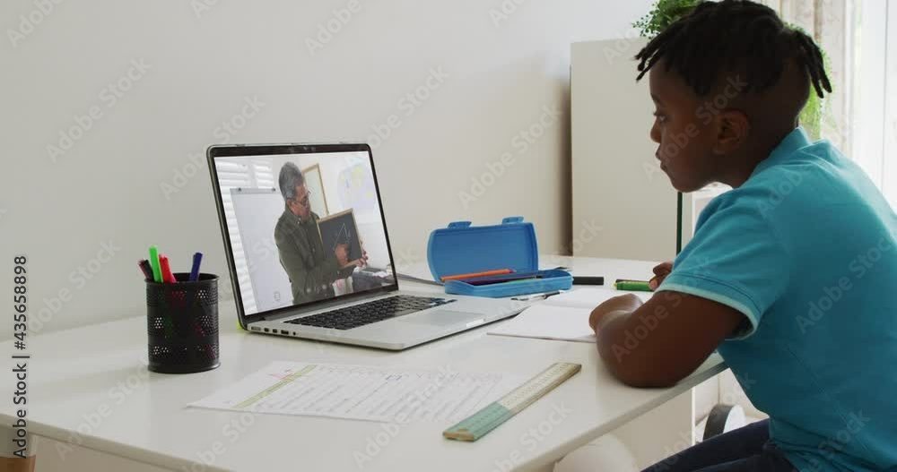 African american boy sitting at desk using laptop having online school lesson African american boy sitting at desk using laptop having online school lesson