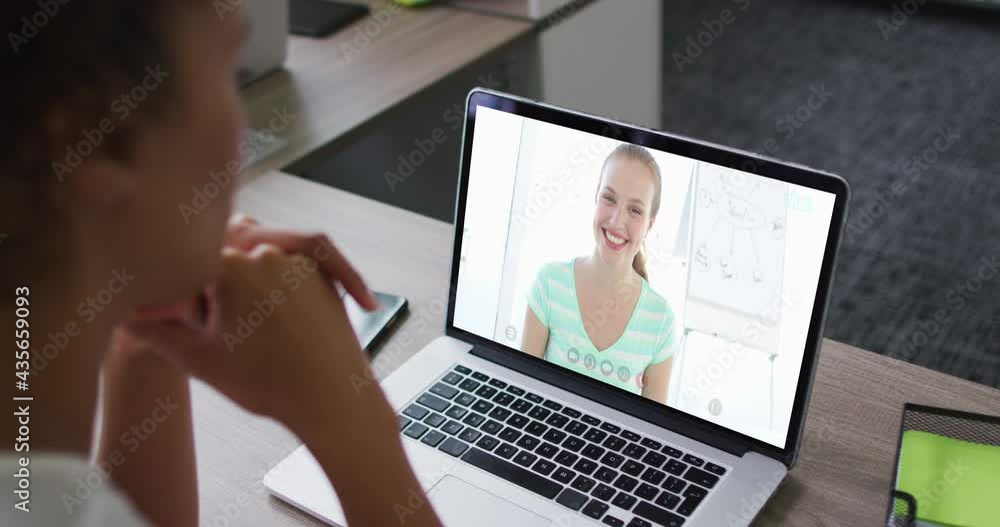 African american businesswoman sitting at desk using laptop having video call with female colleague African american businesswoman sitting at desk using laptop having video call with female colleague