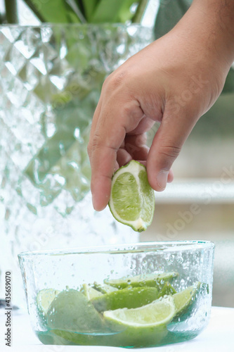 persona toma un limón de una pequeña jarra con limones cortados, frutas ácidas photo