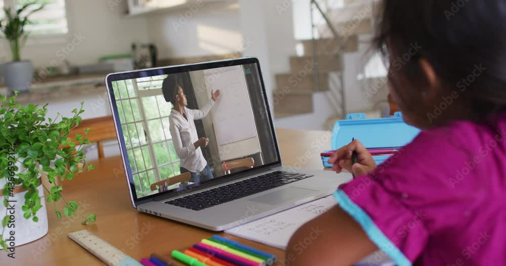 African american girl doing homework while having a video call with female teacher on laptop at home African american girl doing homework while having a video call with female teacher on laptop at home