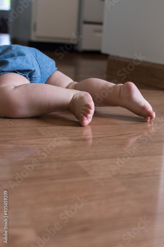 Baby wearing chambray shorts crawling; laminate wood flooring shows reflection of cute baby legs and toes