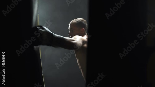 Professional kickboxer training with a boxing bag in a dark gym,smoke. photo