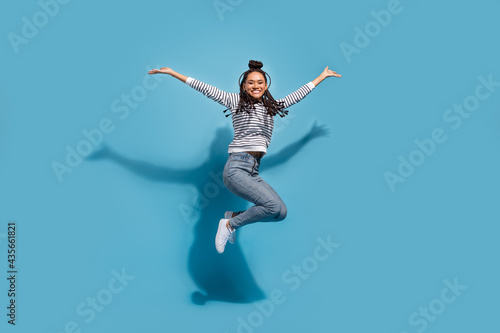 Full length profile side photo of young excited african girl happy positive smile jump up isolated over blue color background