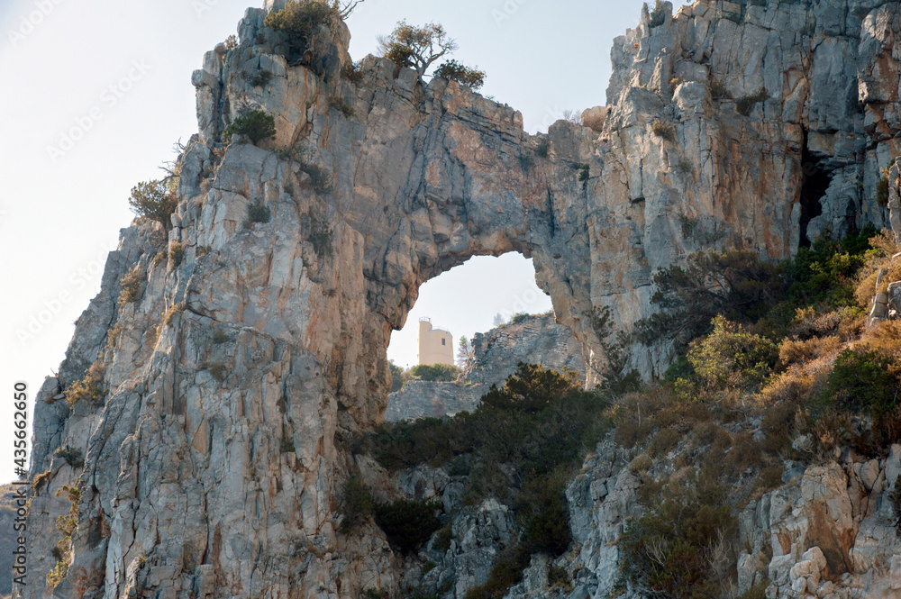 Meteorological station seen from the sea through an arch-shaped opening in the cliff. Palinuro coast, Italy.