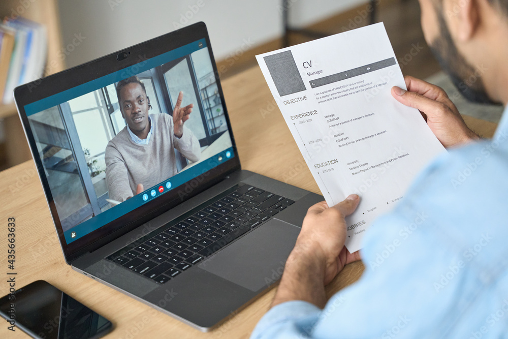 Young indian confident businessman holding cv talking to male black man potential employee hiring for job. Virtual video call between employer and manager worker. Remote recruitment work concept. Young indian confident businessman holding cv talking to male black man potential employee hiring for job. Virtual video call between employer and manager worker. Remote recruitment work concept.
