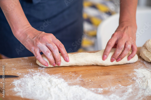 Female hands making dough. Dough with flour, eggs and other utensil, ingredients lies on white wooden table. Baking homemade process.