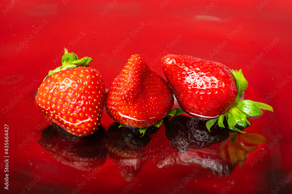 fresh natural strawberries on red background with water fresh natural strawberries on red background with water