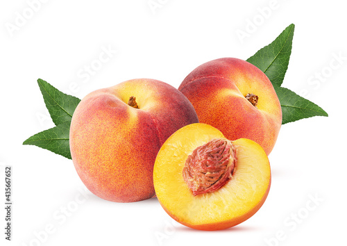 Two ripe peach fruit one cut in half with bone and leaf