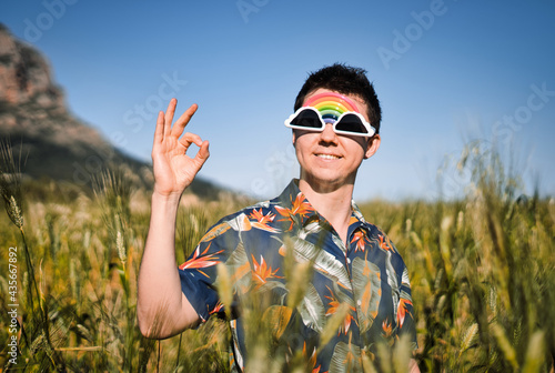 Cool man wearing funny sunglasses smiling and looking at camera in the countryside.
