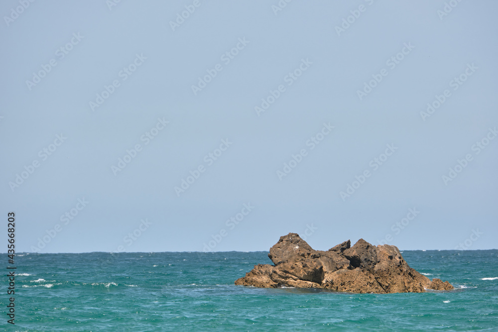 Piedras en medio de un mar turquesa en Cadiz bajo un cielo azul y despejado