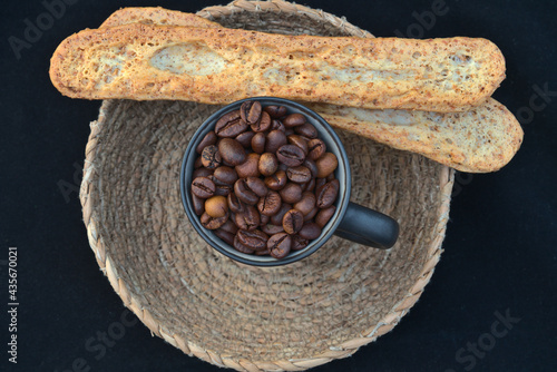 Εκτύπωση καμβά Bodegón que presenta una taza o jarra llena de granos de café, reposando en el centro de un cuenco de cestería sobre el filo del cual se apoyan dos medias baguettes tostadas