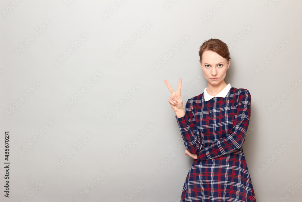 Portrait of serious young woman showing number two with fingers