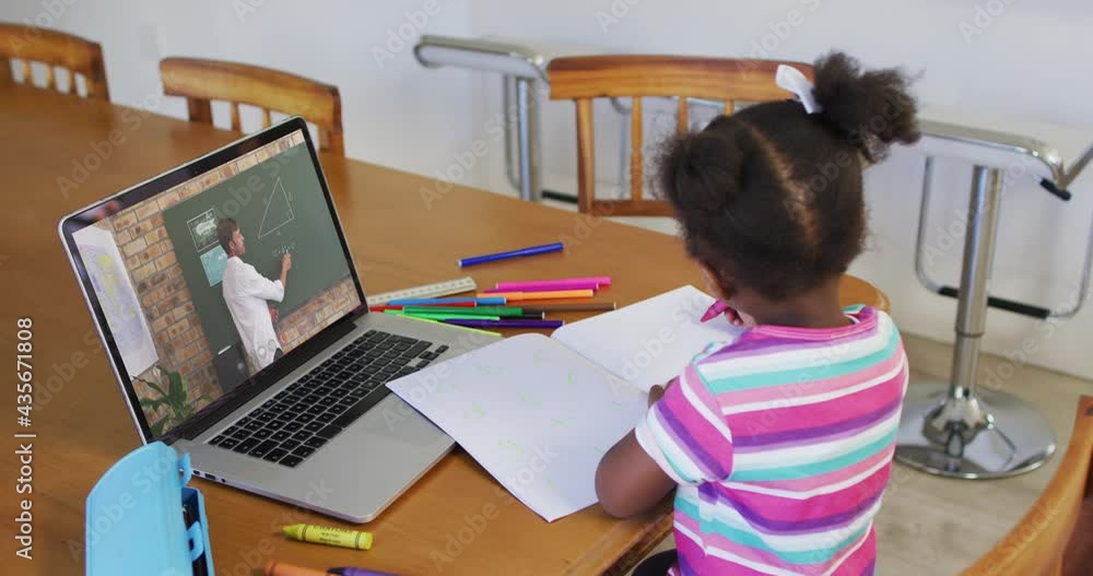 African american girl doing homework while having a video call with male teacher on laptop at home African american girl doing homework while having a video call with male teacher on laptop at home