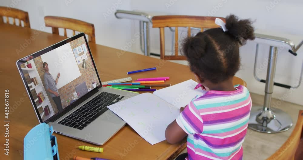 African american girl doing homework while having a video call with male teacher on laptop at home African american girl doing homework while having a video call with male teacher on laptop at home