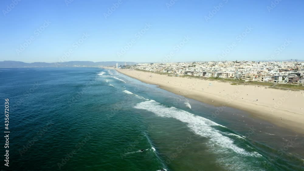 Aerial Panning A Sunny Beach With Crashing Waves, People, Bright Blue Sky, And A Densely Developed Urban Hillside - Manhattan Beach, California Aerial Panning A Sunny Beach With Crashing Waves, People, Bright Blue Sky, And A Densely Developed Urban Hillside - Manhattan Beach, California